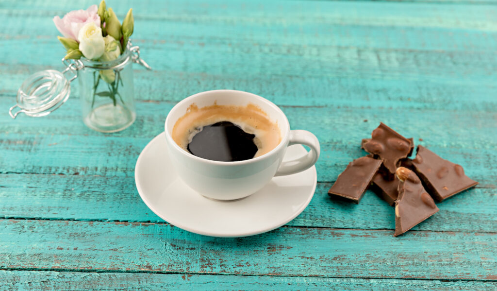 sweet-coffee-and-chocolate-on-teal-background-with-flowers